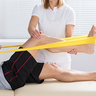 Man Stretching Leg With Physio Band